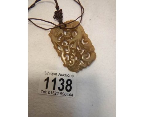 A light brown jade necklace on a feng shui mystic knot