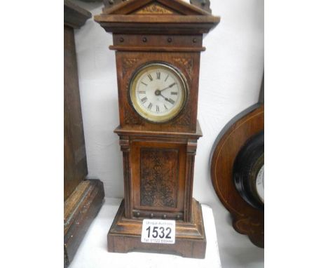An oak mantle clock in the form of a Grandfather clock