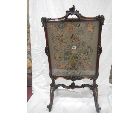A Victorian fire screen with embroidered floral panel under glass