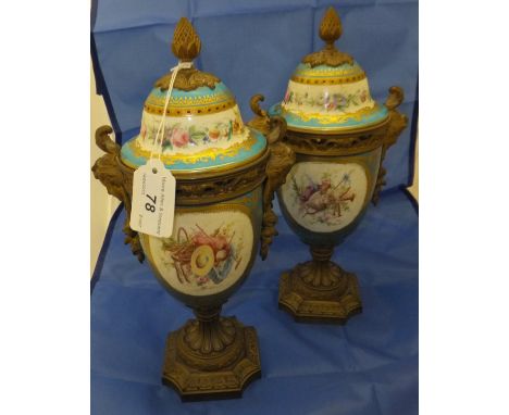 A pair of Sèvres porcelain and gilt bronze mounted urns, each decorated with figures in a garden setting within an enamel bej