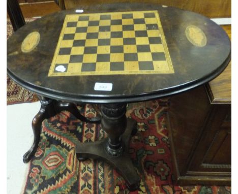 A walnut oval tilt top games table with chequer board insert and shell medallion inlay, raised on baluster turned support to 