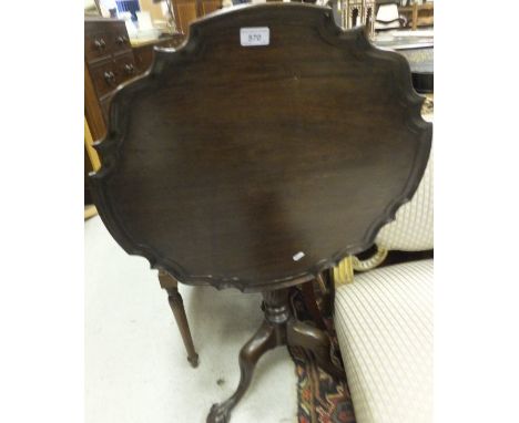 A George III style mahogany tilt-top table, the shaped circular top with pie crust rim, raised on turned and ringed pedestal 