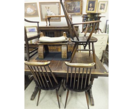 A set of five (4 plus 1) dark elm Ercol stick back chairs, together with an extending rectangular table and a camel stool