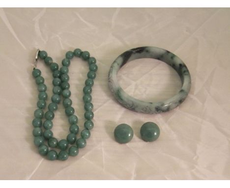 A carved jade bangle with foliate decoration, together with a string of jade beads with clasp stamped "G. Silver" and a pair 