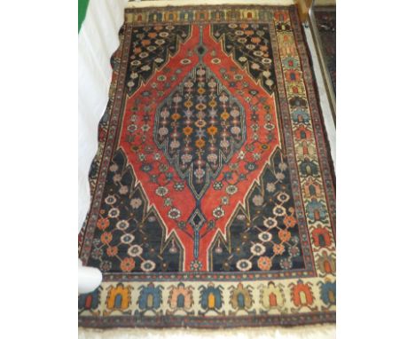A Caucasian rug, the central medallion with rows of floral motifs on a dark blue ground within a red floral decorated diamond