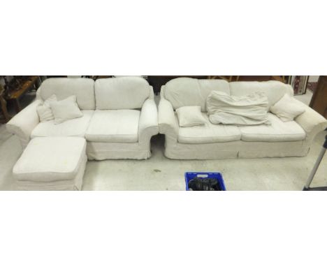 A three seater and two seater sofa in white self patterned foliate upholstery, with matching pouffe