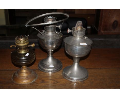A Victorian amber glass and patinated metal oil lamp, together with two chromium plated oil lamps. CONDITION REPORT: Each wit