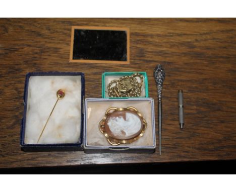 A garnet set yellow metal stick pin, a yellow metal mounted shell cameo brooch, and a yellow metal locket and chain.  CONDITI