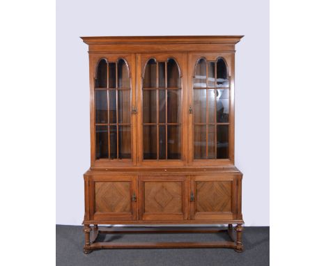 Edwardian walnut bookcase, cavetto cornice above a plain frieze, three glazed doors enclosing adjustable shelves, the base wi