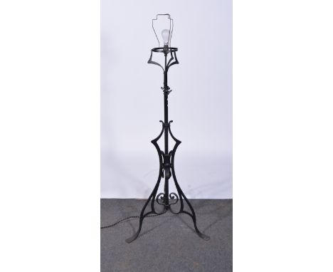 Arts & Crafts style wrought iron standard lamp, shaped base, converted to electricity with later shade, height overall 163cm.