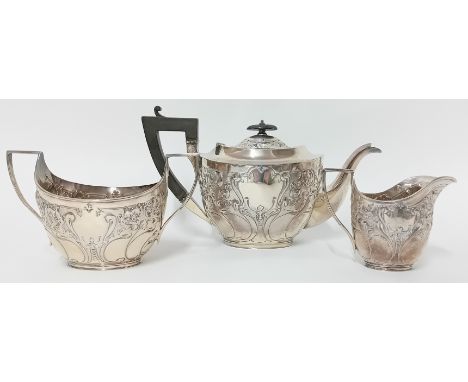 A three piece silver tea service, to include teapot with wooden handle, sugar bowl, and milk jug, of embossed foliate decorat
