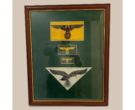A framed collection of Second World War or later German insignia comprising a Factory Police arm band with black eagle facing