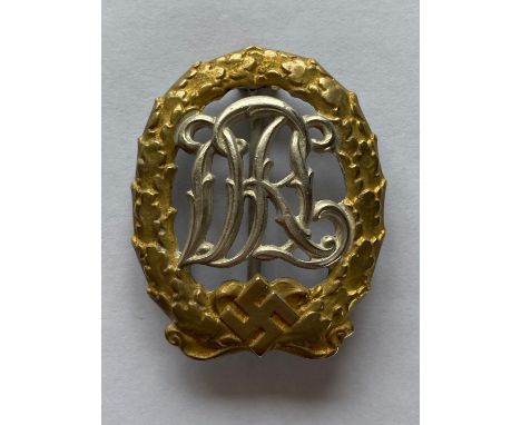 A Second World War German DRL Sports Badge for Wounded Personnel with a gilt wreath, and silver plated scrolling intertwined 