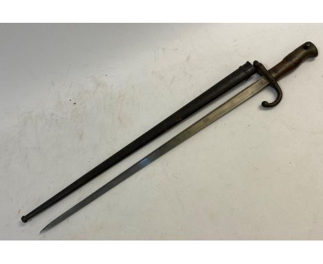 A French bayonet and scabbard with a flat backed, pointed 52cm blade, engraved to the back ' ... St Etiennes ... 1877' the cr