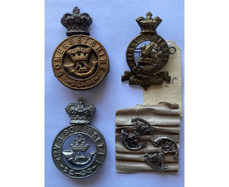 A First Somerset cap badge with a dragon to the centre and 'Defendemus' beneath the garter, on twin lugs, 7 x 5cm, a similar 