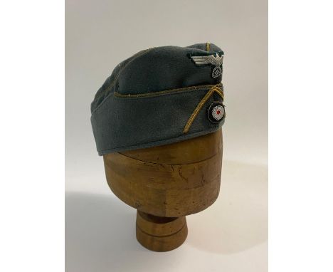 A Second World War German Army Officer's Forage Cap in Fieldgrey material, with gold bullion piping, possibly indicating the 