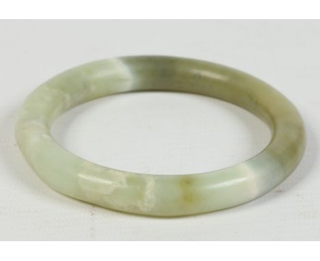 A Chinese mottled mutton fat celadon jade bangle of slightly irregular form. 60.98 grams, 6.5cm and 8.75cm wide Condition Rep