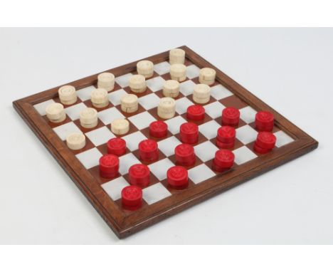 An oak mounted opaque glass checkers board along with two sets of turned bone counters, opposing side stained in ox blood red