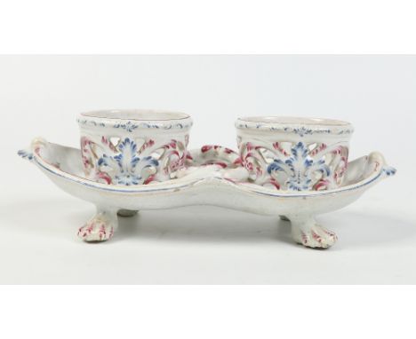 A nineteenth century Continental faience cruet stand. Moulded with rococo scrolls edged in puce, blue enamel and raised on pa