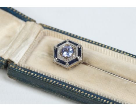 A cased 14 carat white gold Art Deco stick pin. With hexagonal terminal set with sapphires and a brilliant cut blue topaz sto