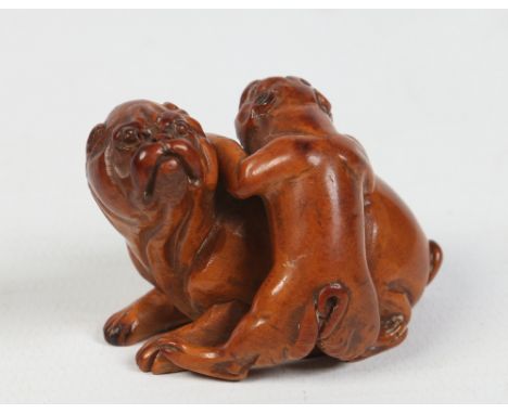 A Japanese carved fruitwood netsuke formed as a pug dog and pup,  5cm. Condition Report. To be used as a guide only. Good con