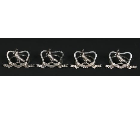 A set of four Edwardian silver place name holders by Brook and Son. Mounted with a bird holding an arrow in its beak over a s