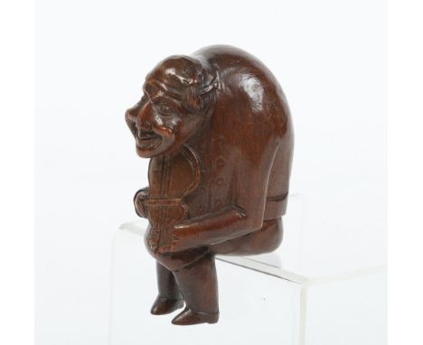 A nineteenth century Black Forest carved figural nut cracker. Formed as a hunched back man playing a fiddle, and with a lead 