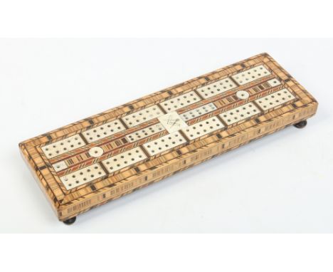 A nineteenth century cribbage board raised on turned feet. Inlaid with specimen woods, bone and incised with a Masonic motif,