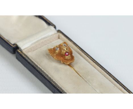 A cased yellow metal stick pin with a lion mask terminal set with diamonds and a ruby, 2.56 grams. Unmarked. Condition Report