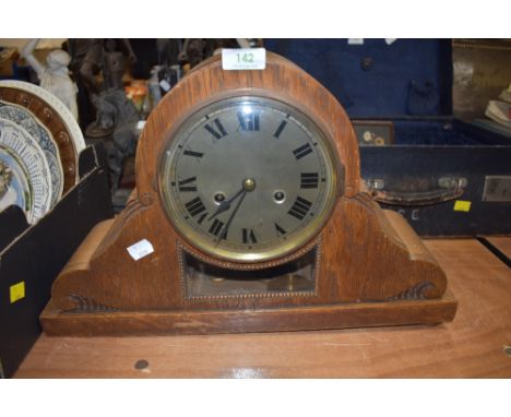 An ornate oak framed mantle clock having glass window and visible mechanism with chime