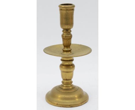 A mid 17th Century Dutch cast brass 'Heemskirk' candlestick, with turned stem, wide central drip pan and mound base, 19.5cm.