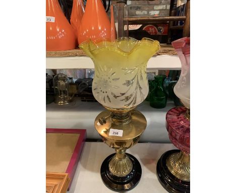 A YELLOW GLASS AND BRASS OIL LAMP ON A METAL BASE 