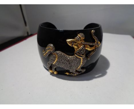 A HEAVY BLACK BANGLE WITH A GOLD AND DIAMOND DECORATION IN THE FORM OF SAGITTARIUS 