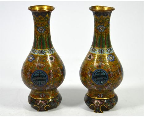 A pair of Chinese cloisonné vases, enamelled with Shou symbols on a ground of stylised flowering plants snd having integral b