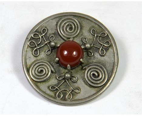 A round Celtic style brooch set with Carnelian stone, 10mm Carnelian claw set in centre of pewter metal. Diameter 3.5cm.