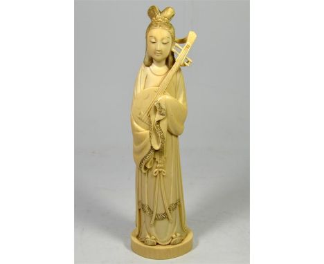 λ A Japanese ivory okimono of a female musician playing a shamisen. Meiji Period. Signed to red lacquer seal. Height 27.5cm.