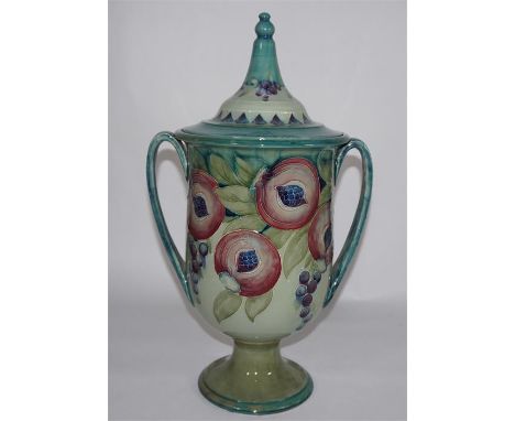 A William Moorcroft 'Pomegranate' urn and lid, decorated on a light green ground, circa 1910. Signed William Moorcroft. Heigh
