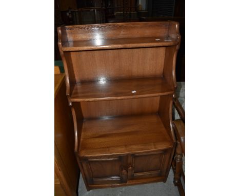 An Ercol mid elm tiered bookshelf with cupboard base