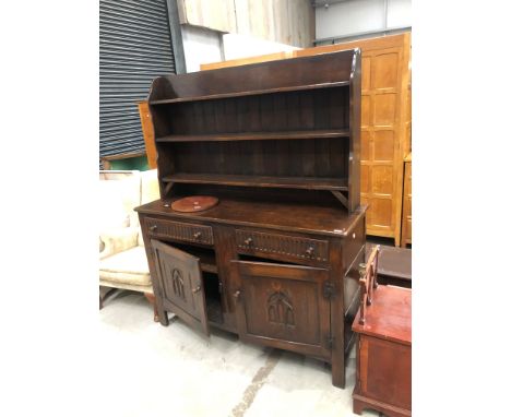 An early 20th Century dark oak dresser having Gothic style decoration to doors and shelf back