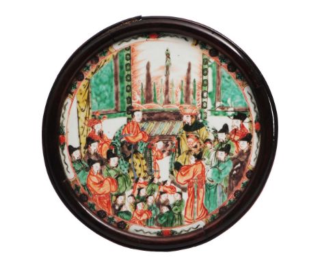 A Chinese famille verte roundel Kangxi (1662-1722) painted with a court scene within a hardwood frame, 21cm across