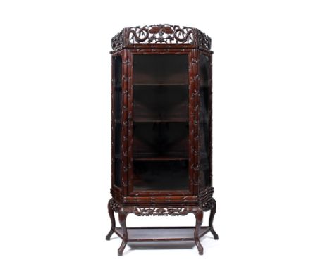 A Chinese rosewood display cabinet 19th Century with glazed hinged door and sides, with fruit carved frieze and bamboo sides 