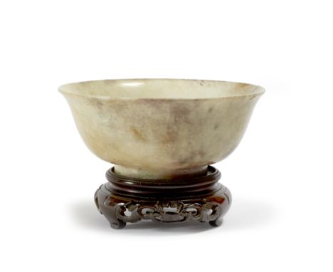 A Chinese burnt jade bowl Ming Dynasty (1368-1644) of pale oatmeal tone with greyish-mauve blue with touches of green, excava
