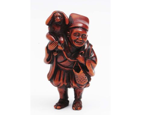 A Japanese wood netsuke of a Sarumawashi 18th Century the figure having monkey upon his right shoulder, the left carrying a b