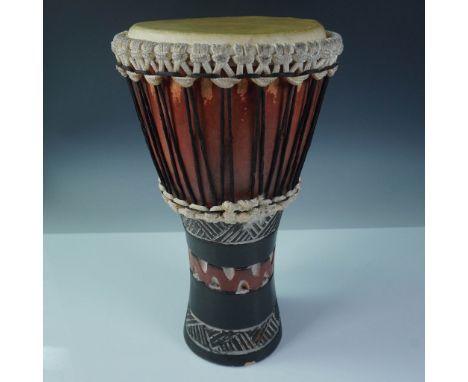 Hand-carved West African-style djembe drum featuring a goblet-shaped body and rich tribal inspired carvings on the base. The 