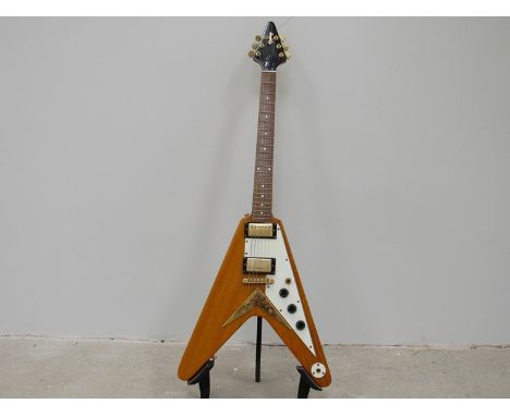 A Gibson Epiphone flying V electric guitar with amber natural body, white pickguard and gold coloured hardware 