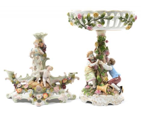 A GERMAN FLORAL ENCRUSTED PORCELAIN FIGURAL FRUIT STAND, THE RETICULATED BOWL PAINTED WITH FLOWERS ON SHELL MOULDED GILT FOOT