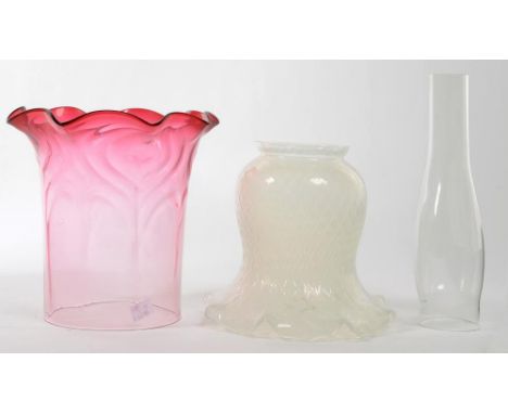 A CRANBERRY SHADED GLASS LAMP SHADE WITH FRILLED RIM AND RIPPLED MOULDING, 21CM H, ANOTHER AND A GLASS LAMP CHIMNEY