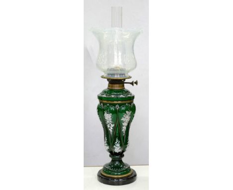 A VICTORIAN ENAMELED GREEN GLASS OIL LAMP, THE DETACHABLE FOUNT WITH BRASS BURNER AND A SEMI OPALESCENT GLASS SHADE, ON BLACK