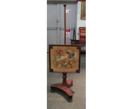 A mahogany pole fire screen with embroidered screen of flowers on plateau base
