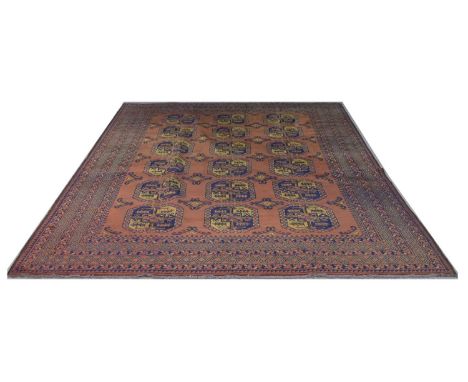 Afghan carpet, decorated with gul medallions on an orange/red ground, 300 x 197cms. 